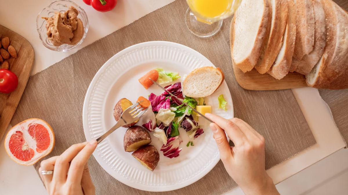 Top view of a nutritious breakfast setup with salad, bread, and fresh juice, perfect for a healthy start.
